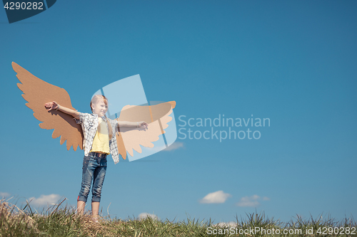 Image of Little girl playing with cardboard toy wings in the park at the 