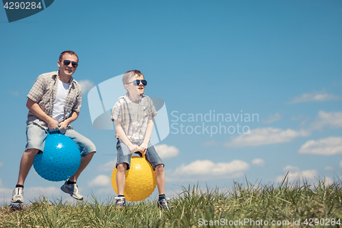 Image of Father and son playing on the field at the day time.