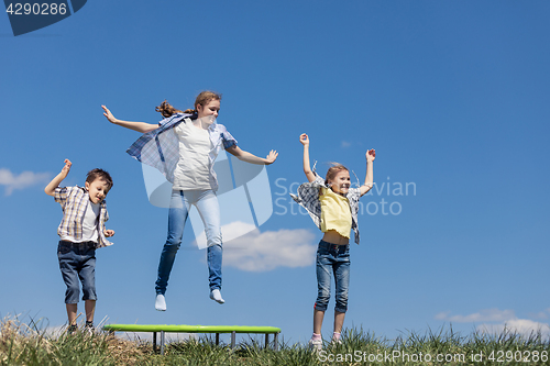 Image of Brother and sisters playing on the field at the day time.