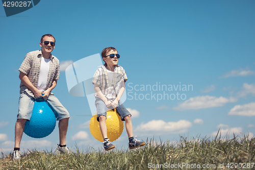 Image of Father and son playing on the field at the day time.