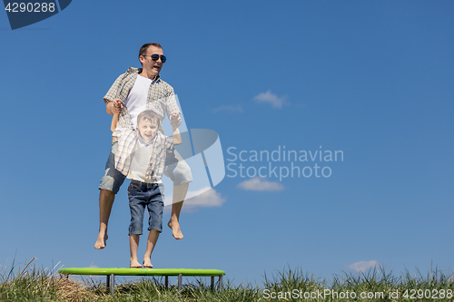 Image of Father and son playing on the field at the day time.