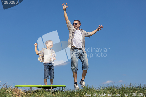 Image of Father and son playing on the field at the day time.