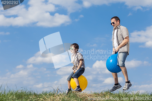 Image of Father and son playing on the field at the day time.