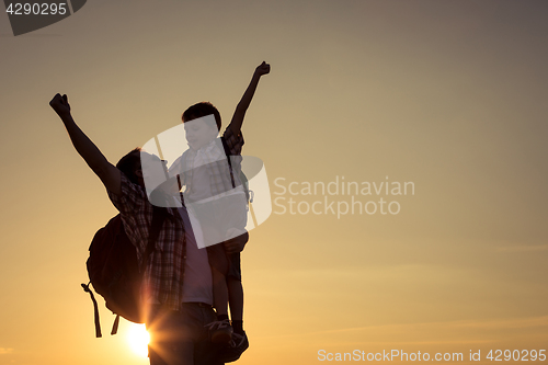 Image of Father and son walking on the field at the sunset time.