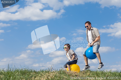 Image of Father and son playing on the field at the day time.