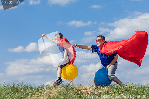 Image of Father and son playing superhero at the day time.