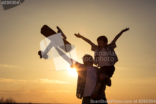 Image of Father and son playing with cardboard toy airplane in the park a