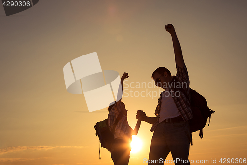 Image of Father and son walking on the field at the sunset time.