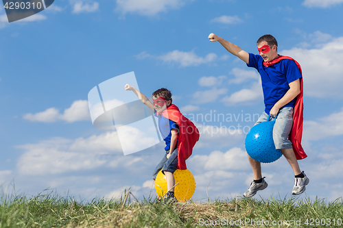 Image of Father and son playing superhero at the day time.