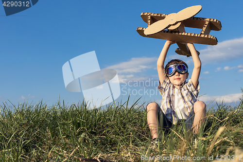 Image of Little boy playing with cardboard toy airplane in the park at th