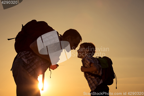 Image of Father and son walking on the field at the sunset time.