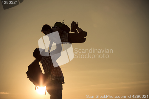 Image of Father and son walking on the field at the sunset time.