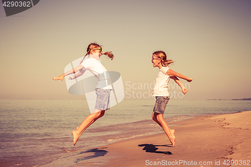 Image of Two sisters playing on the beach at the day time.