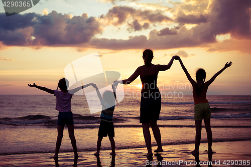 Image of Mother and children playing on the beach at the sunset time.