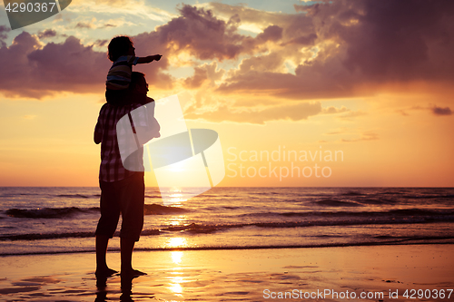 Image of Father and son playing on the beach at the sunset time.