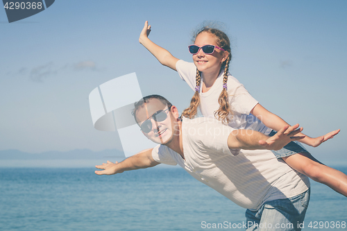 Image of Father and daughter playing on the beach at the day time.