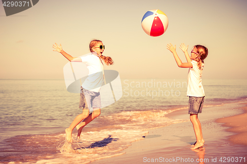 Image of Two sisters playing on the beach at the day time.