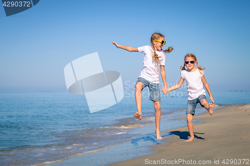 Image of Two sisters playing on the beach at the day time.