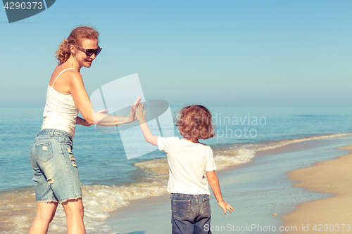 Image of Mother and son playing on the beach at the day time.