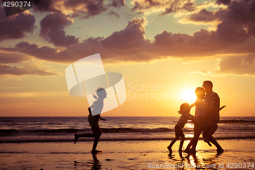 Image of Father and children playing on the beach at the sunset time.