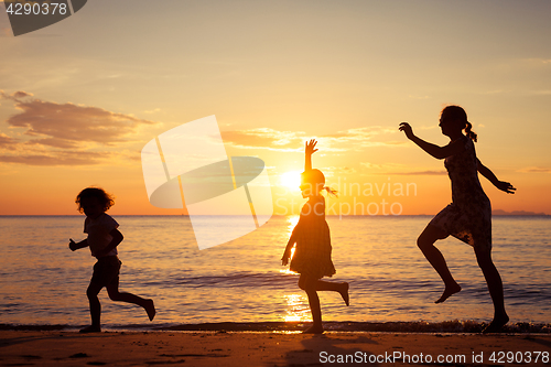 Image of Mother and children playing on the beach at the sunset time.