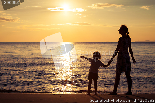 Image of Mother and son playing on the beach at the sunset time.