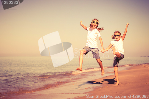 Image of Two sisters playing on the beach at the day time.