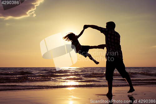 Image of Father and son playing on the beach at the sunset time.