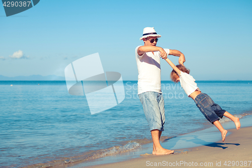 Image of Father and son playing on the beach at the day time.