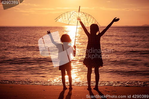 Image of Happy children playing on the beach at the sunset time.