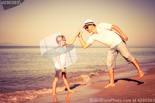 Image of Father and daughter playing on the beach at the day time.