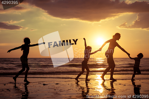 Image of Mother and children playing on the beach at the sunset time.