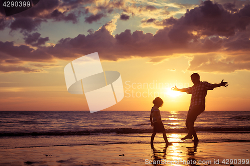 Image of Father and son playing on the beach at the sunset time.