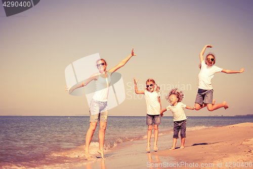 Image of Mother and children playing on the beach at the day time.