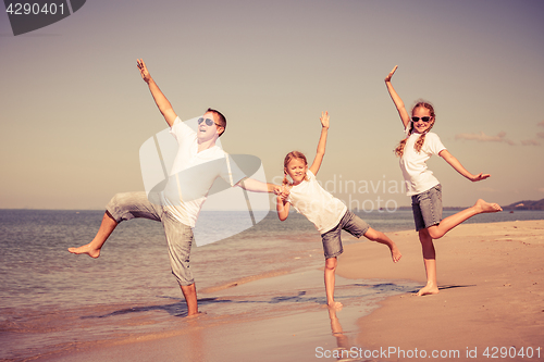 Image of Father and daughters playing on the beach at the day time.