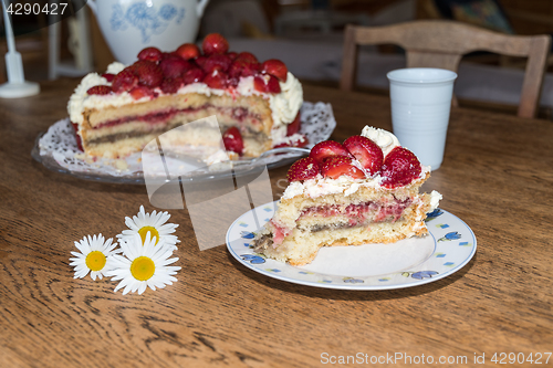 Image of Cut piece of strawberry cake on a plate at a table