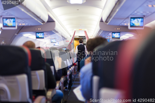 Image of Interior of commercial airplane with passengers on seats during flight.