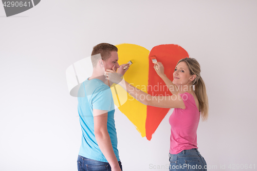 Image of couple are painting a heart on the wall