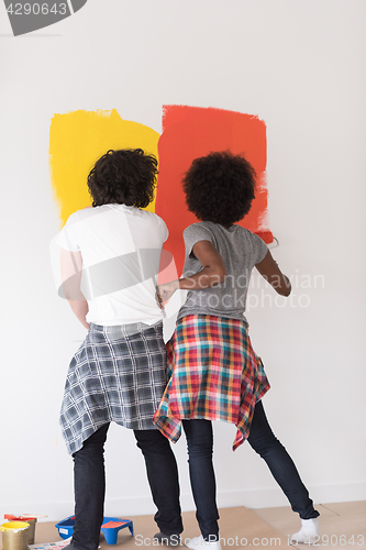 Image of multiethnic couple painting interior wall