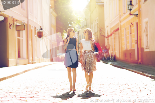 Image of happy women with shopping bags walking in city