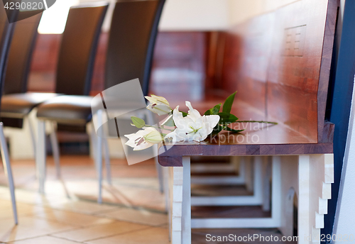 Image of white lily on bench at funeral in church