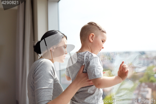 Image of mother and son looking through window at home