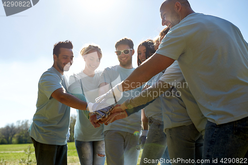 Image of group of volunteers putting hands on top outdoors