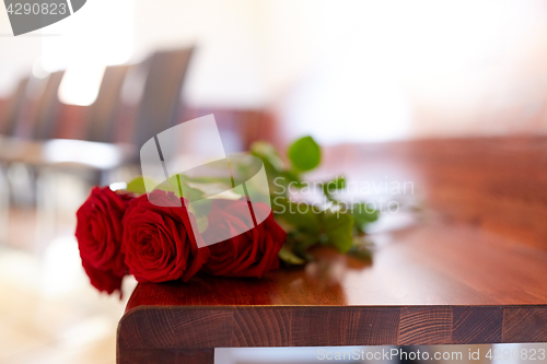 Image of red roses on bench at funeral in church