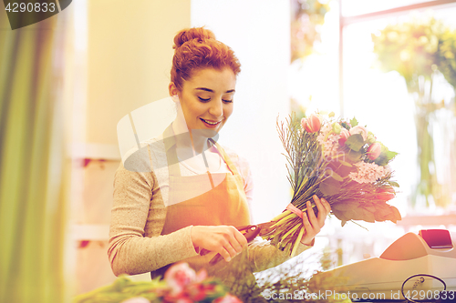 Image of smiling florist woman making bunch at flower shop