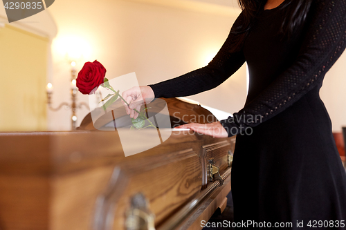 Image of woman with red roses and coffin at funeral