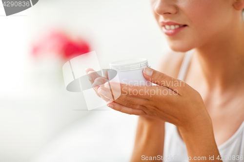 Image of close up of happy woman holding and smelling cream