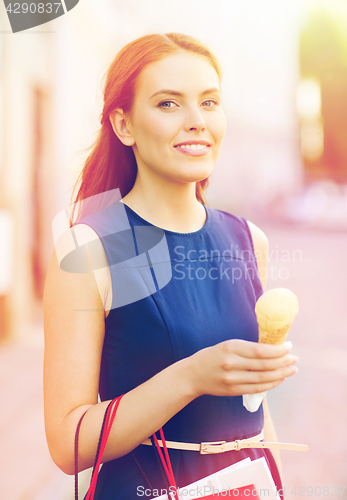 Image of woman with shopping bags and ice cream in city