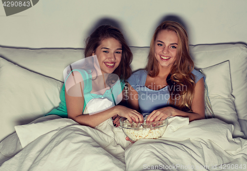 Image of happy friends with popcorn and watching tv at home