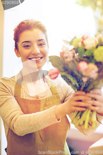 Image of smiling florist woman making bunch at flower shop